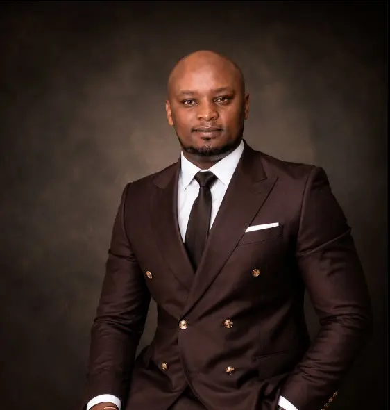 Studio portrait of Ken Murithi in a brown double-breasted suit